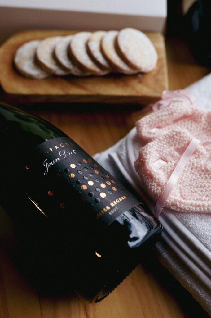 Caja gourmet recién mamá con toalla y babero bordado, patucos y champagne